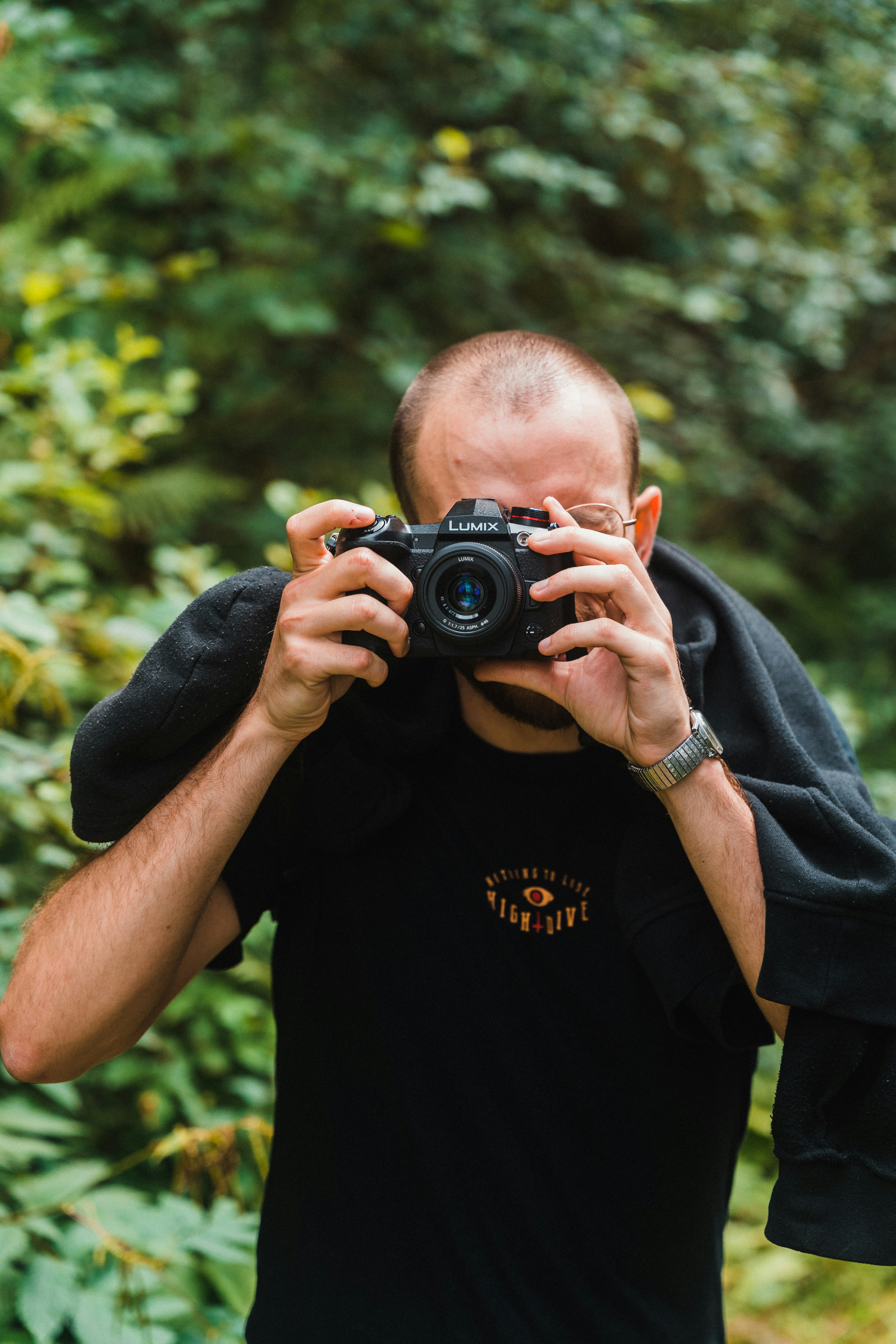 man in black crew neck t-shirt holding black dslr camera